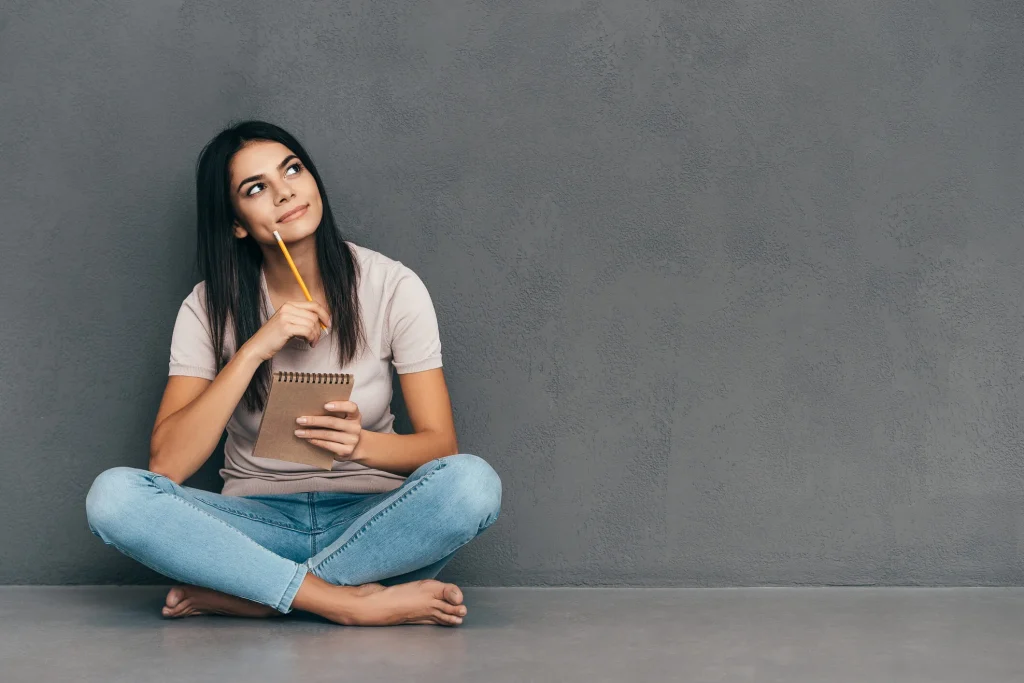 Photo of a girl sitting crisscrossed infront of a black wall thinking about what is a title loan