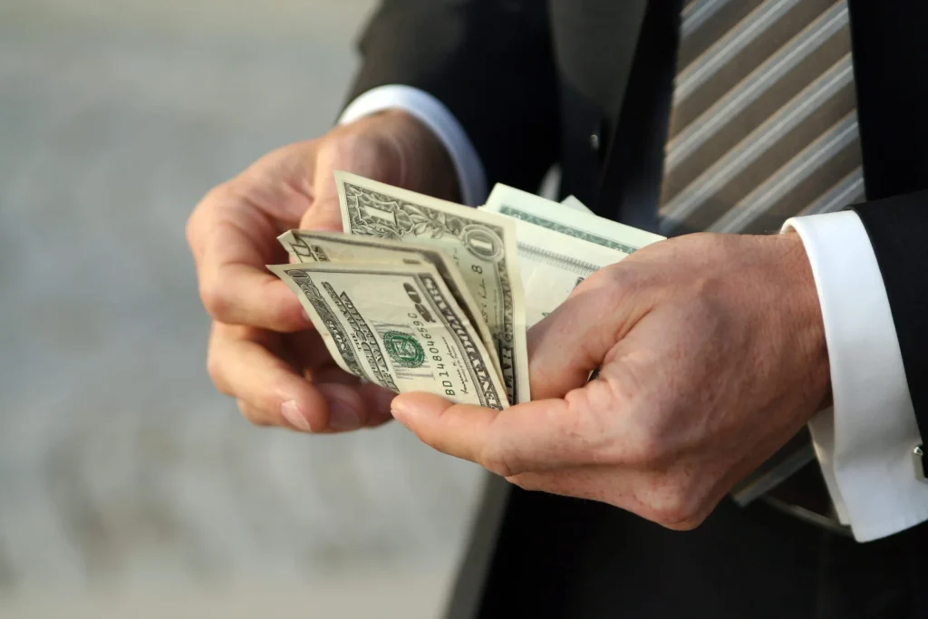 This is a photo of a man in a suit counting his cash, which represents people avoiding overpaying for title loans