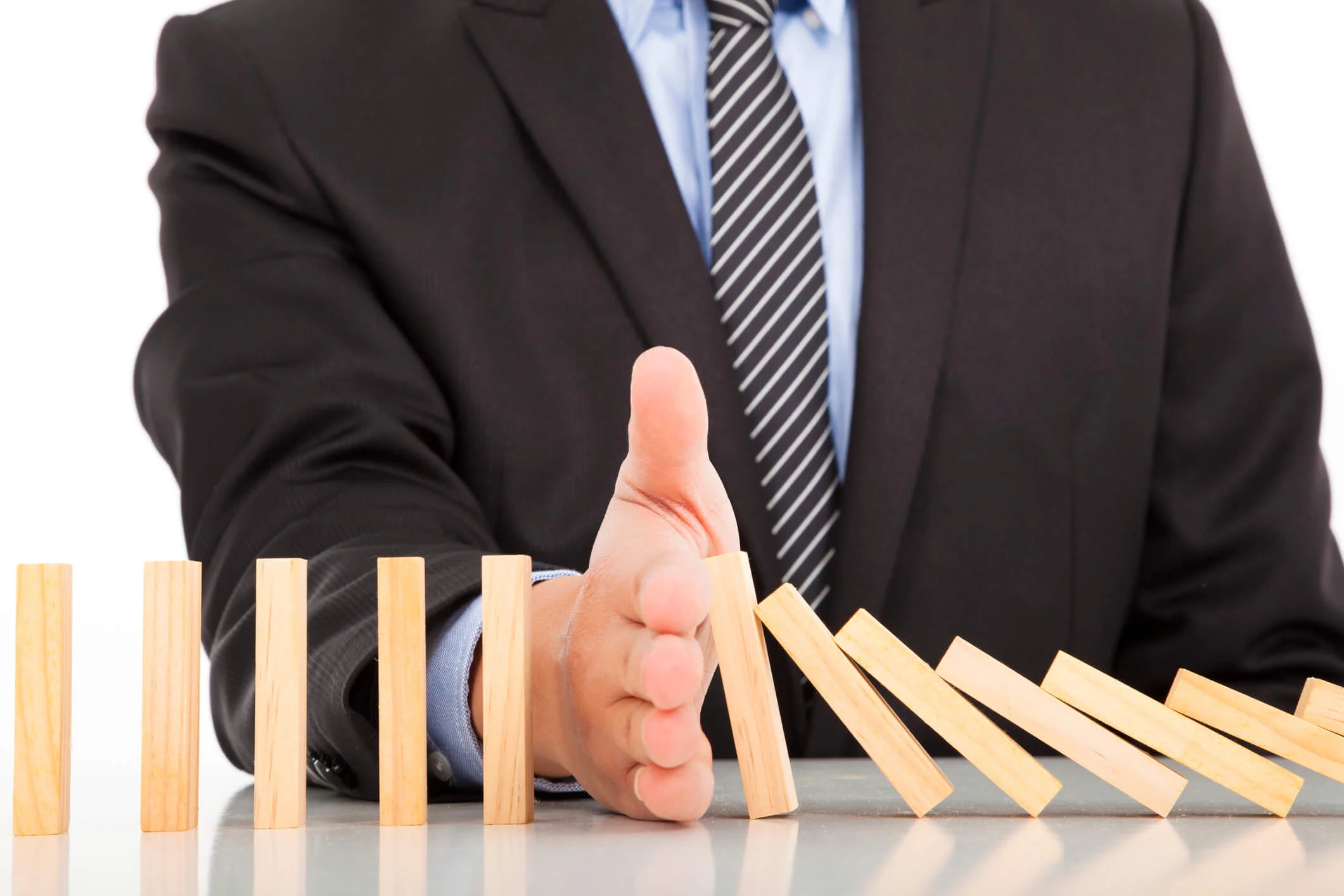 This is a photo of a man in a suit stopping dominoes from falling over.