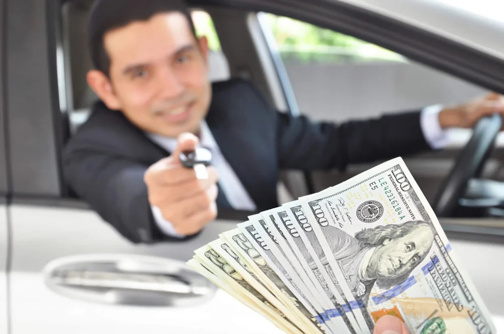 Photo of a man giving his car keys for money to represent how you can pawn your car and drive.