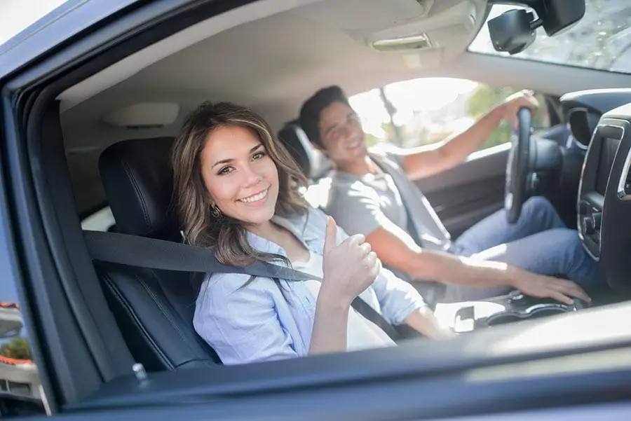 photo of two people buying a car smiling and giving a thumbs up